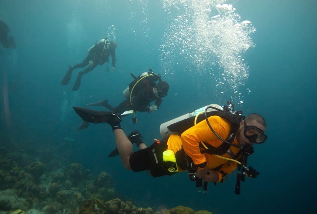 Diver in orange wetsuit with buddies