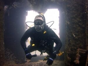 Scuba diver exploring underwater shipwreck interior.