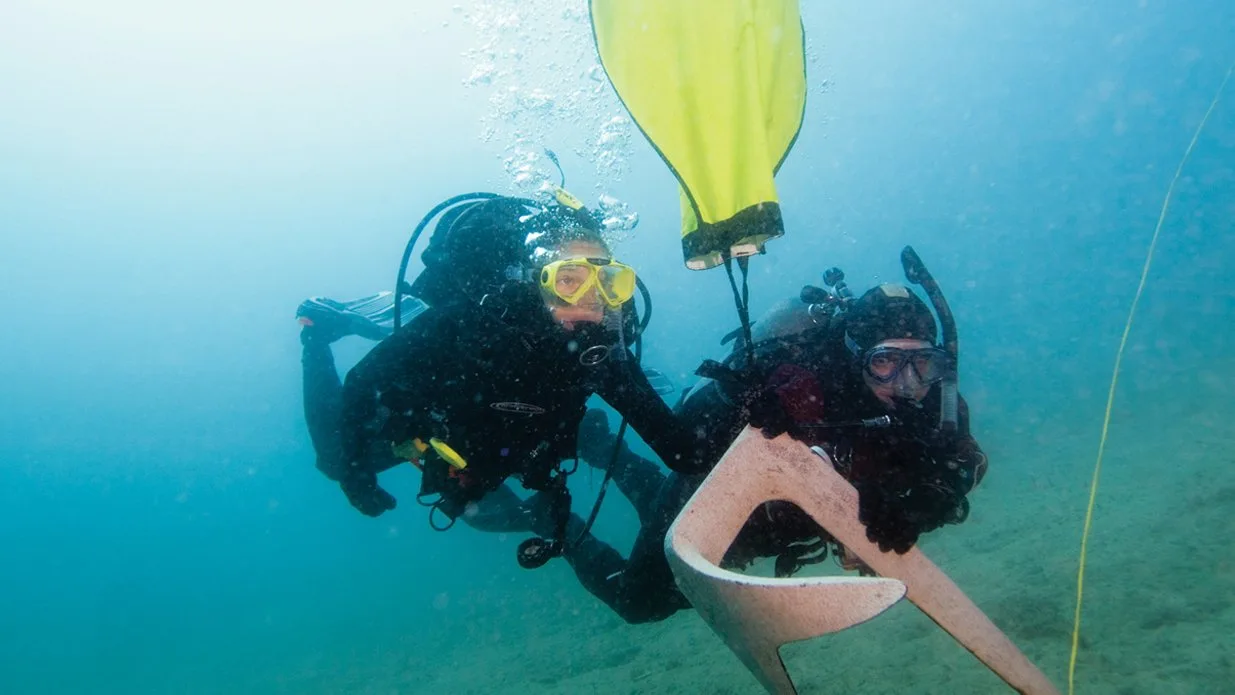 Scuba divers underwater with yellow buoy.