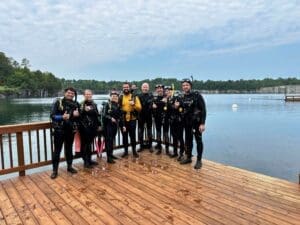 Group of divers on wooden dock, lake background.