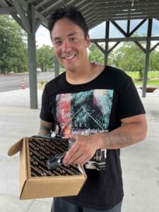 Man smiling with a box outdoors.