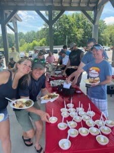 Group enjoying outdoor picnic with food table.
