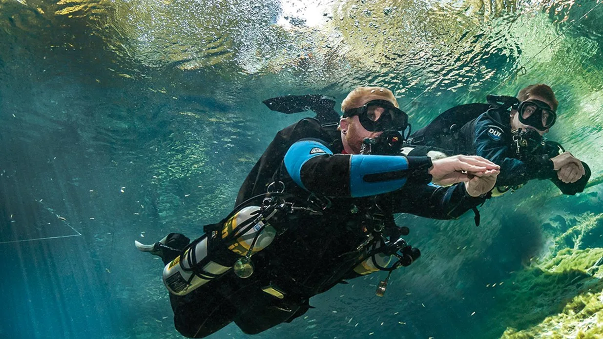 Two scuba divers exploring clear green water